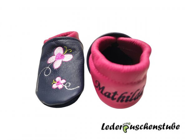 Lederpuschen dunkelblau-pink mit Namen links und Datums rechte Ferse dunkelblau sowie Stickerei Schildi 2 pink-rosa-hellgrün Schmetterlinge 